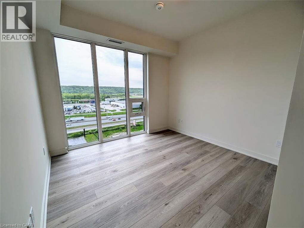 Spare room featuring light wood-style floors and expansive windows - 385 Winston Road Unit# 1311, Grimsby, ON - Indoor Photo Showing Other Room