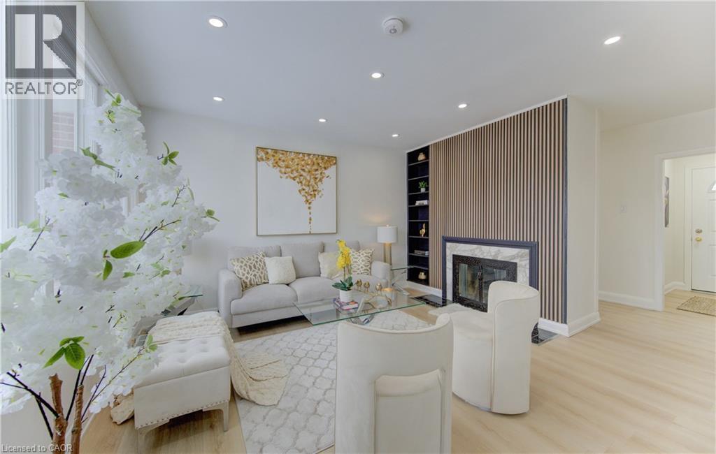 Living room featuring light wood-style flooring, recessed lighting, a premium fireplace, and built in shelves - 171 Sixth Avenue, Kitchener, ON - Indoor Photo Showing Living Room With Fireplace