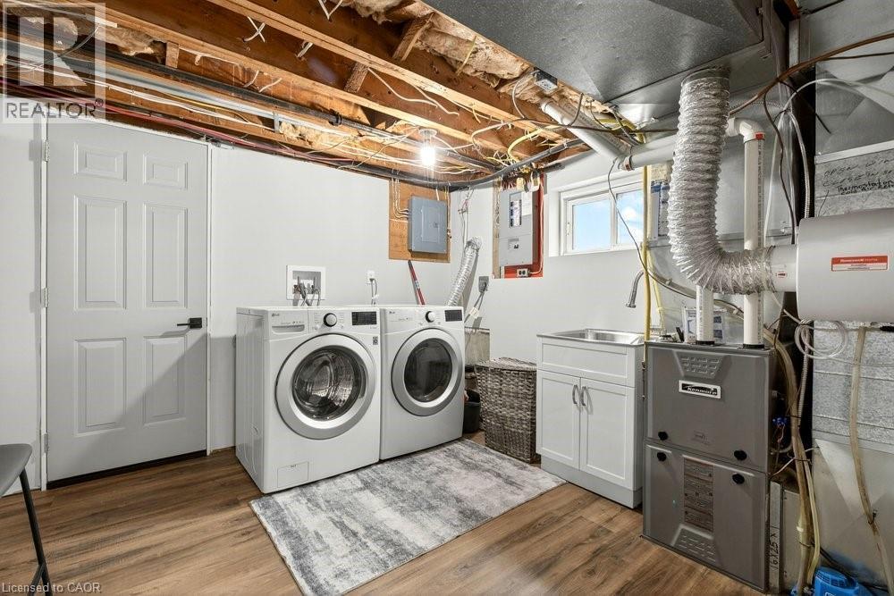 Laundry area with dark wood-style flooring, washing machine and clothes dryer, electric panel, and heating unit - 237 East 32Nd Street, Hamilton, ON - Indoor Photo Showing Laundry Room
