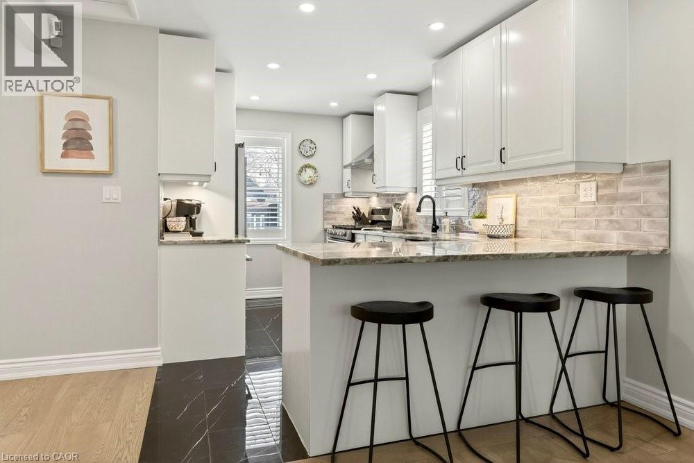 Kitchen with white cabinets, light stone countertops, stainless steel range with gas stovetop, a peninsula, and recessed lighting - 237 East 32Nd Street, Hamilton, ON - Indoor Photo Showing Kitchen With Upgraded Kitchen