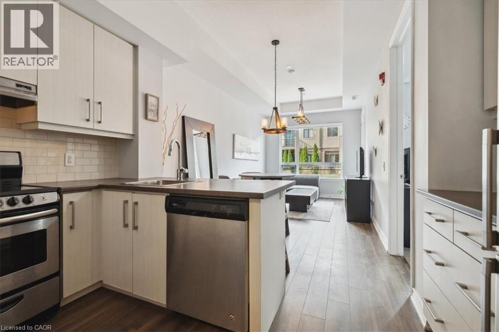 Kitchen with stainless steel appliances, a peninsula, backsplash, dark wood finished floors, and dark countertops - 40 Esplanade Lane Unit# 102, Grimsby, ON - Indoor Photo Showing Kitchen With Upgraded Kitchen