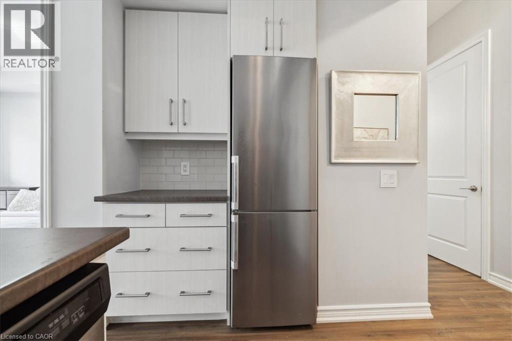 Kitchen with stainless steel appliances, dark countertops, dark wood-style floors, and tasteful backsplash - 40 Esplanade Lane Unit# 102, Grimsby, ON - Indoor Photo Showing Kitchen