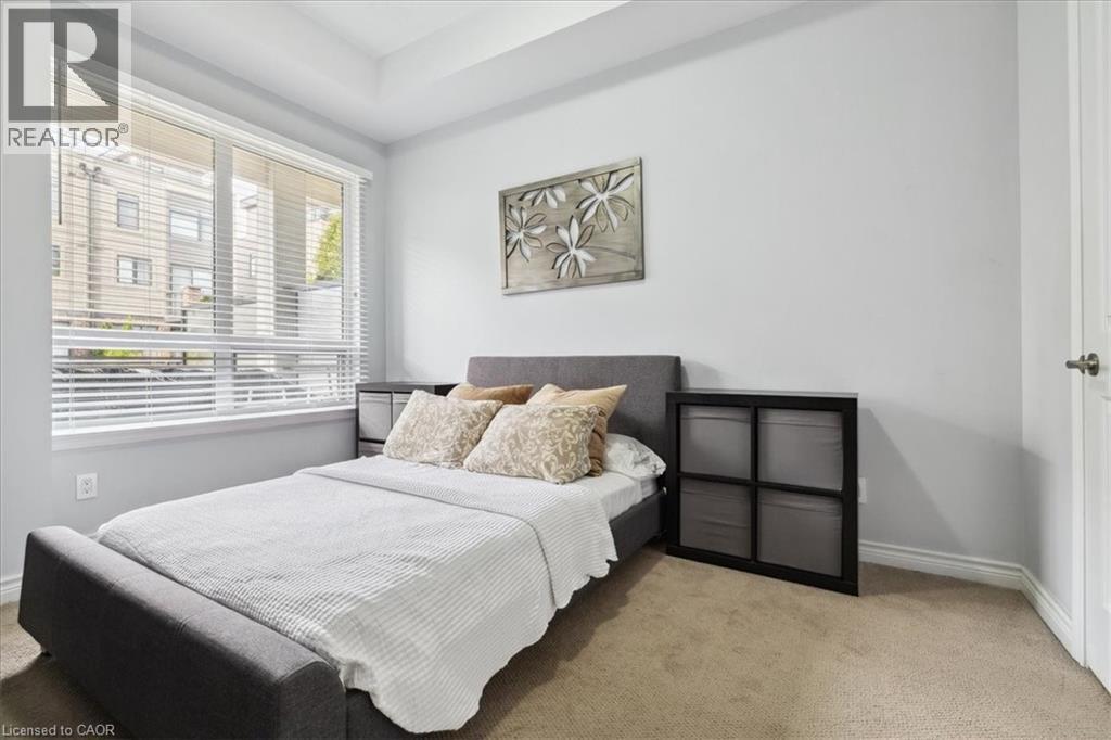 Bedroom featuring light carpet and baseboards - 40 Esplanade Lane Unit# 102, Grimsby, ON - Indoor Photo Showing Bedroom