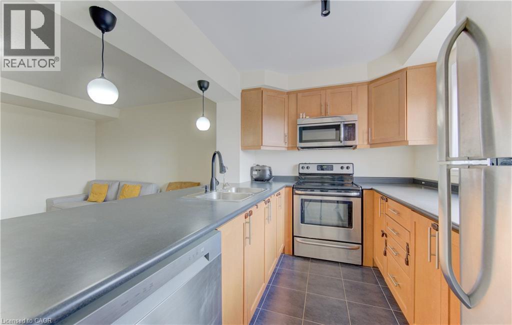Kitchen featuring stainless steel appliances, decorative light fixtures, light wood finish cabinetry, dark tile patterned flooring, and light countertops - 9 Outlook Terrace, Kitchener, ON - Indoor Photo Showing Kitchen With Stainless Steel Kitchen