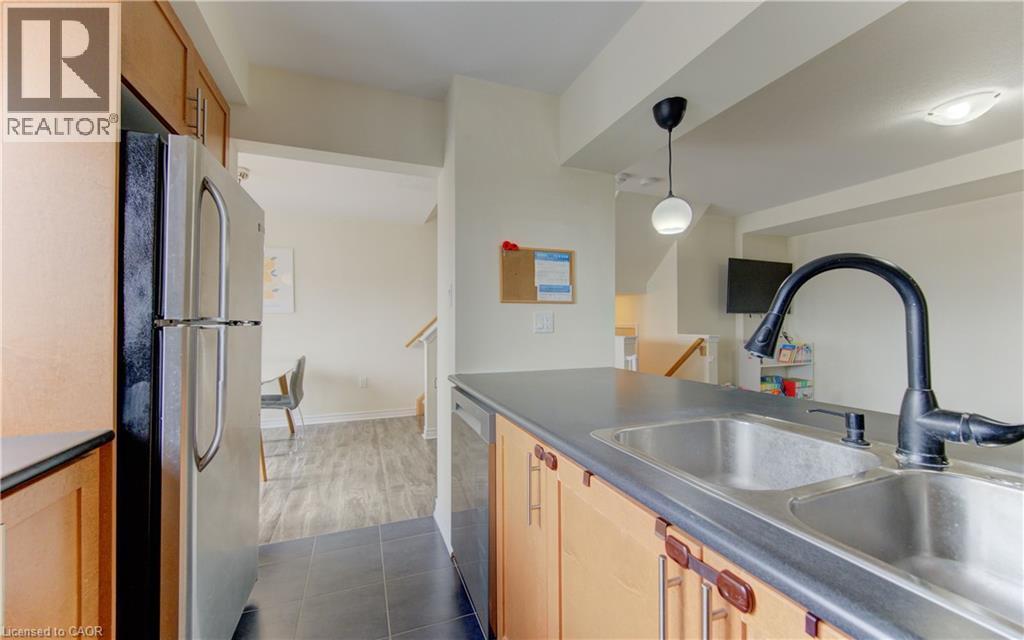 Kitchen featuring stainless steel appliances, dark countertops, light wood finish cabinetry, dark tile patterned flooring, and decorative light fixtures - 9 Outlook Terrace, Kitchener, ON - Indoor Photo Showing Kitchen With Double Sink
