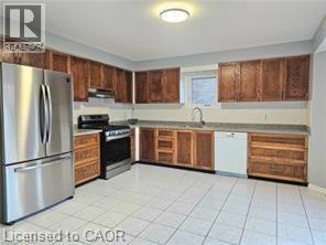Kitchen with stainless steel appliances, light countertops, light tile patterned floors, and wood finish cabinetry - 486 Dicenzo Drive, Hamilton, ON - Indoor Photo Showing Kitchen