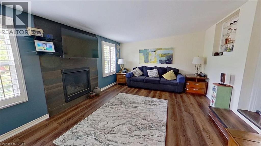 Living room featuring dark wood finished floors and a glass covered fireplace - 27 Hepburn Avenue, St. Thomas, ON - Indoor Photo Showing Living Room With Fireplace