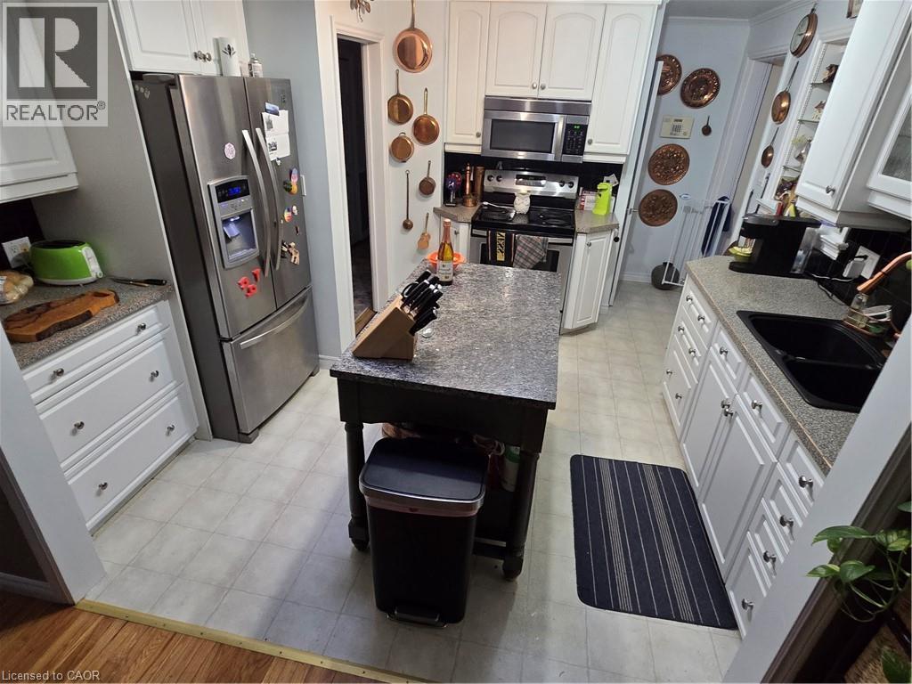 Kitchen featuring stainless steel appliances, white cabinetry, light flooring, and dark stone countertops - 27 Hepburn Avenue, St. Thomas, ON - Indoor Photo Showing Kitchen With Double Sink
