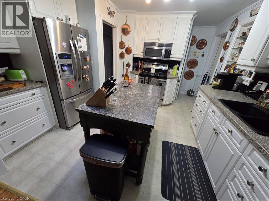 Kitchen with white cabinets, stainless steel appliances, light flooring, dark stone countertops, and crown molding - 27 Hepburn Avenue, St. Thomas, ON - Indoor Photo Showing Kitchen