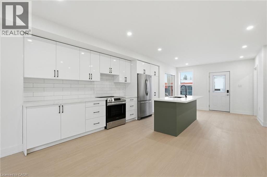 Two tone kitchen with stainless steel appliances, light wood finished floors, tasteful backsplash, an island with sink, and recessed lighting - 1278 Main Street E, Hamilton, ON - Indoor Photo Showing Kitchen With Stainless Steel Kitchen With Upgraded Kitchen