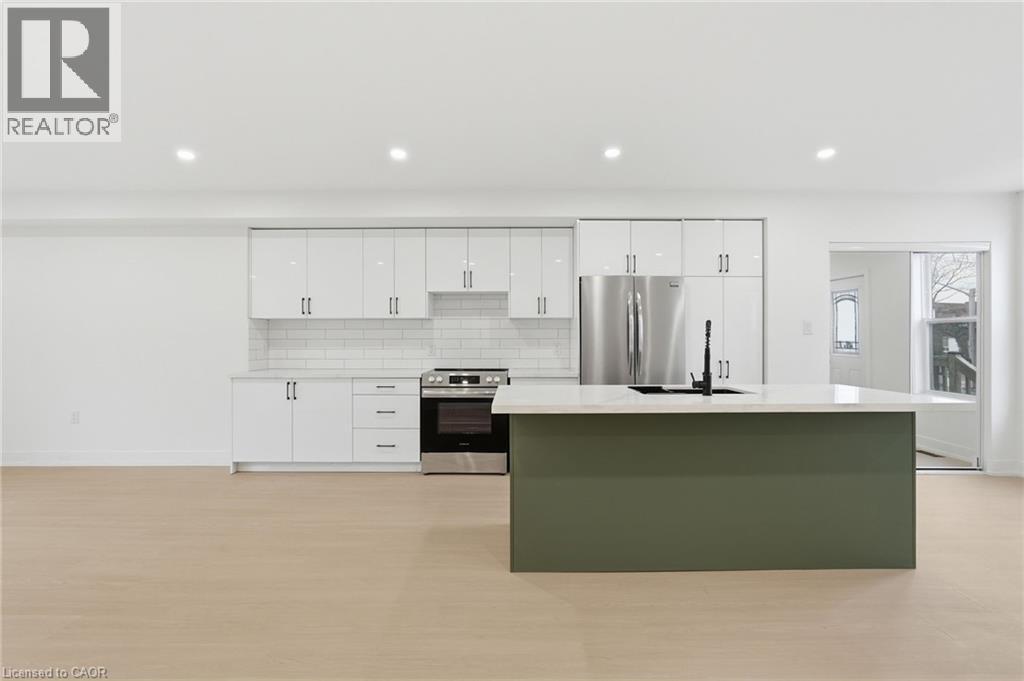 Dual tone kitchen featuring stainless steel appliances, a center island with sink, backsplash, recessed lighting, and light stone countertops - 1278 Main Street E, Hamilton, ON - Indoor Photo Showing Kitchen With Stainless Steel Kitchen With Upgraded Kitchen