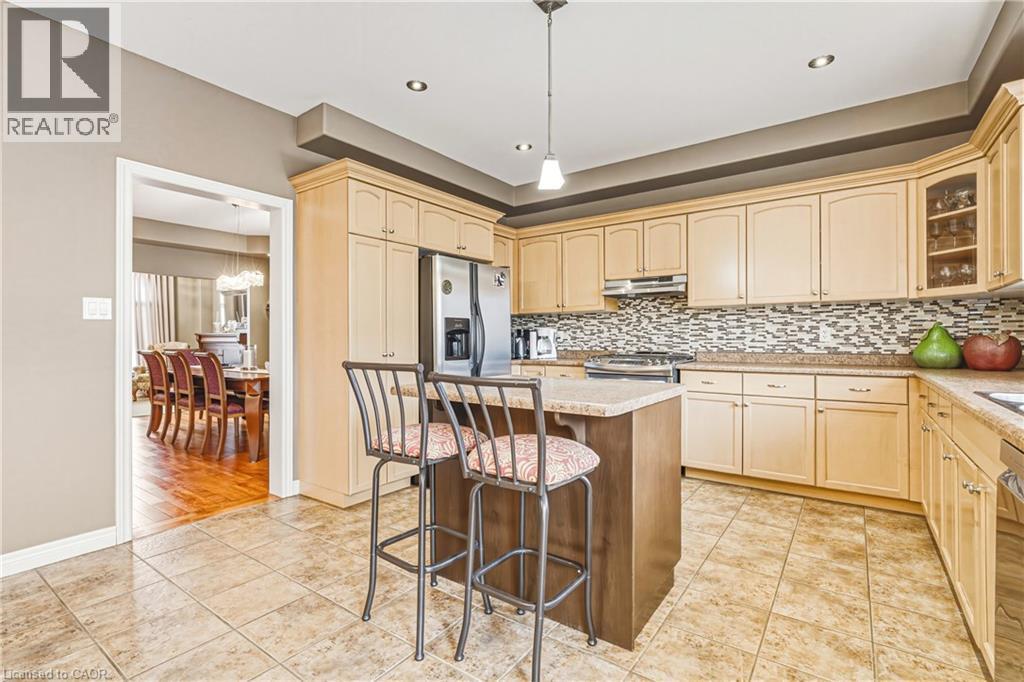 Kitchen featuring pendant lighting, stainless steel appliances, a kitchen island, glass insert cabinets, and a kitchen bar - 120 Valiant Circle, Hamilton, ON - Indoor Photo Showing Kitchen With Upgraded Kitchen