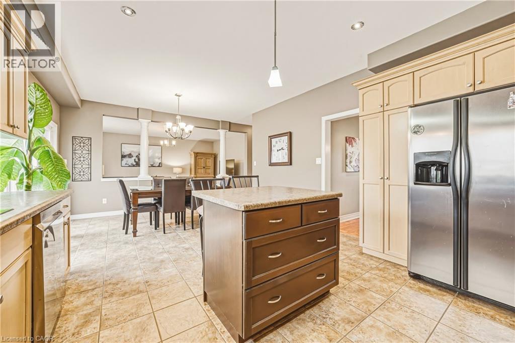 Kitchen with stainless steel appliances, a center island, light countertops, hanging lights, and light tile patterned floors - 120 Valiant Circle, Hamilton, ON - Indoor Photo Showing Kitchen
