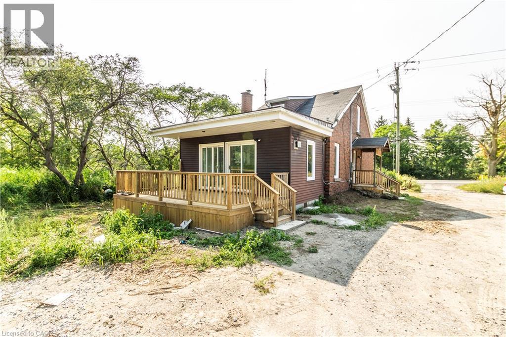 Bungalow-style house with a chimney and a wooden deck - 1411 E 56 Highway, Glanbrook, ON - Outdoor