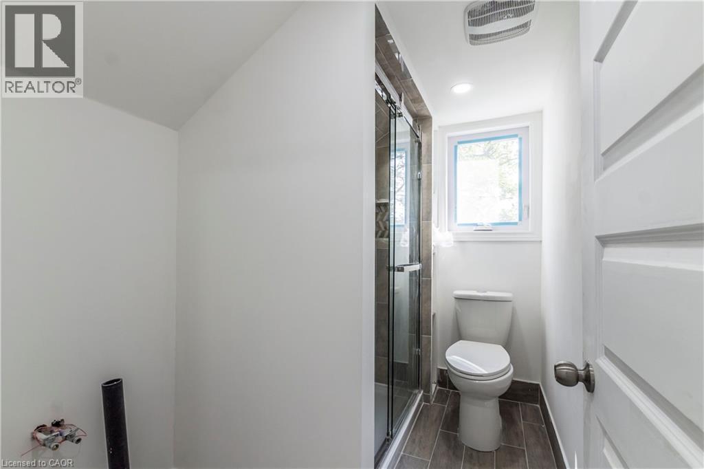 Full bath featuring a shower stall, vaulted ceiling, and wood finish floors - 1411 E 56 Highway, Glanbrook, ON - Indoor Photo Showing Bathroom