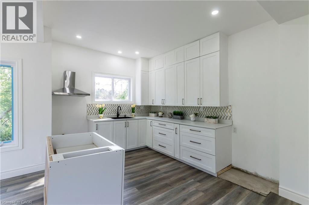 Kitchen with white cabinets, backsplash, dark wood-type flooring, and recessed lighting - 1411 E 56 Highway, Glanbrook, ON - Indoor Photo Showing Laundry Room