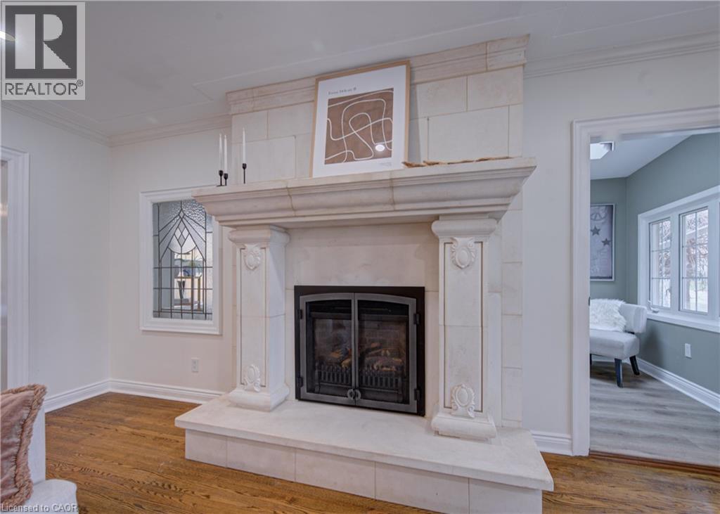 Detailed view of ornamental molding, a fireplace with raised hearth, and wood finished floors - 655 Ellengale Road, Burlington, ON - Indoor With Fireplace