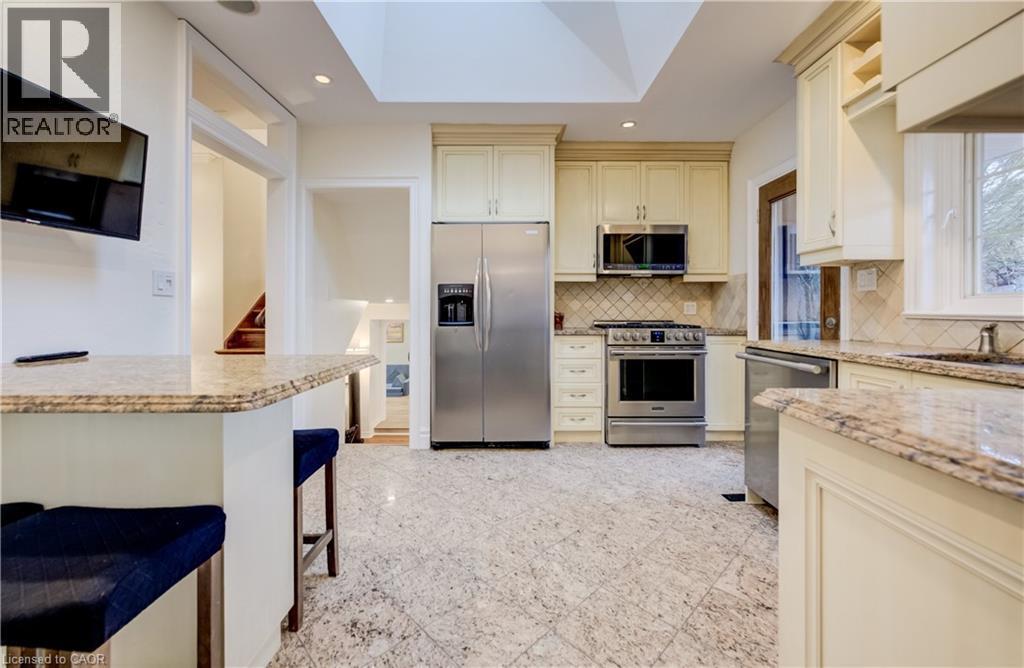 Kitchen with stainless steel appliances, light stone countertops, cream cabinetry, and recessed lighting - 655 Ellengale Road, Burlington, ON - Indoor Photo Showing Kitchen With Upgraded Kitchen