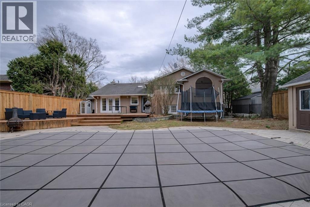 View of swimming pool with a fenced backyard, a trampoline, patio surround, a wooden deck, and french doors - 655 Ellengale Road, Burlington, ON - Outdoor With In Ground Pool