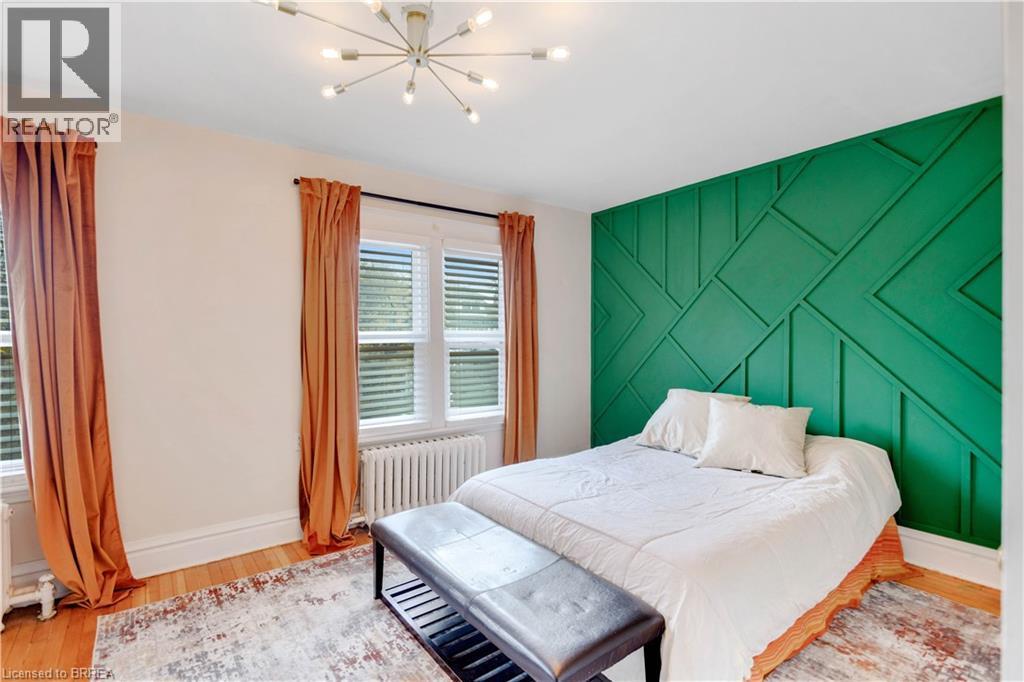 Bedroom featuring an accent wall, radiator, light wood-style flooring, and a chandelier - 134 Sherman Avenue S, Hamilton, ON - Indoor Photo Showing Bedroom