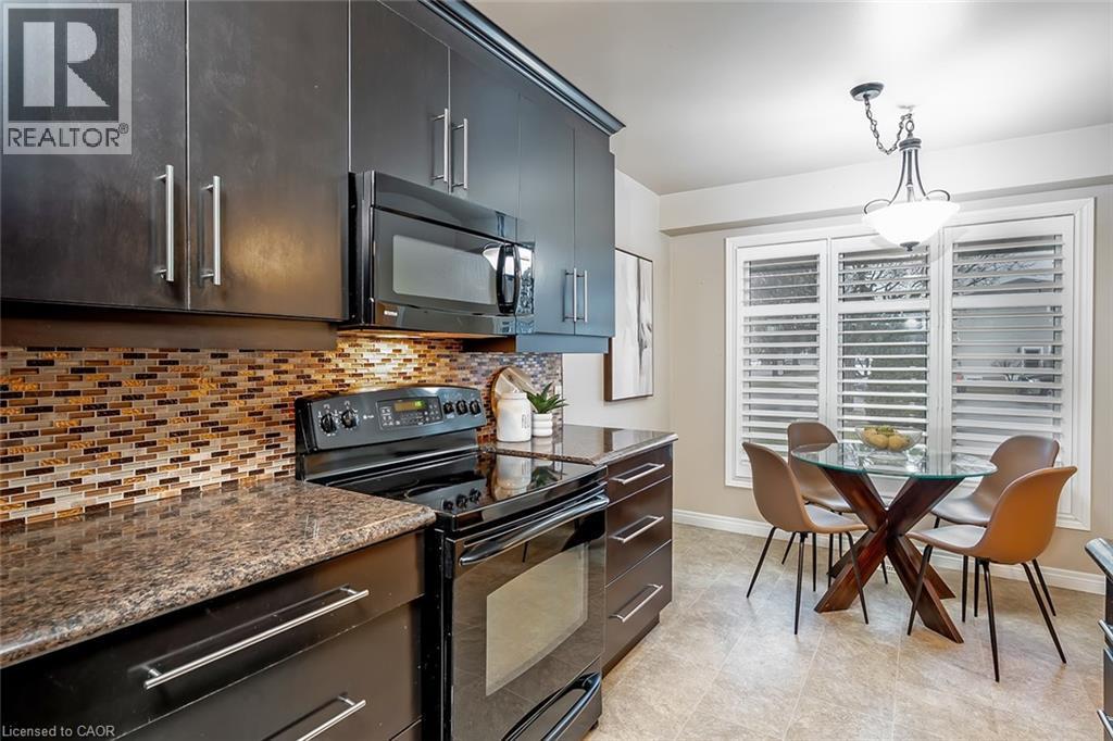 Kitchen with black appliances, hanging light fixtures, dark stone counters, and backsplash - 1278 Consort Crescent, Burlington, ON - Indoor