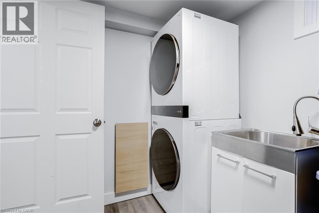Laundry room featuring stacked washing machine and dryer and light wood-type flooring - 624 Burgess Avenue, Hamilton, ON - Indoor Photo Showing Laundry Room