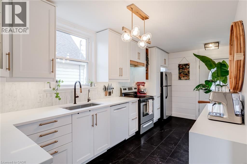Kitchen with stainless steel electric range oven, white cabinetry, freestanding refrigerator, pendant lighting, and dishwasher - 624 Burgess Avenue, Hamilton, ON - Indoor Photo Showing Kitchen