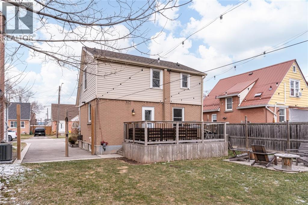 Rear view of property with a lawn, a deck, brick siding, and an outdoor fire pit - 624 Burgess Avenue, Hamilton, ON - Outdoor