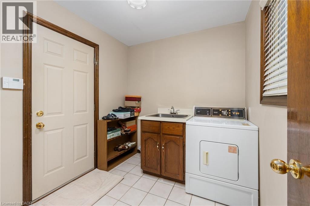 Laundry area featuring washer / clothes dryer, light tile patterned flooring, and cabinet space - 57 Derek Drive, Hamilton, ON - Indoor Photo Showing Laundry Room