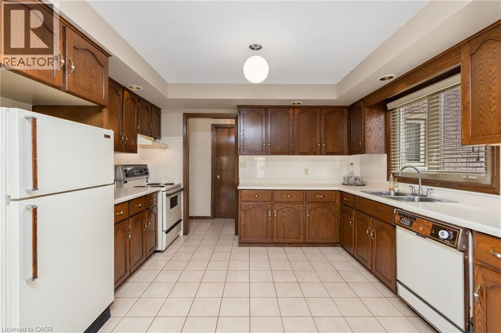 Kitchen featuring white appliances, light countertops, light tile patterned floors, recessed lighting, and tasteful backsplash - 57 Derek Drive, Hamilton, ON - Indoor Photo Showing Kitchen With Double Sink
