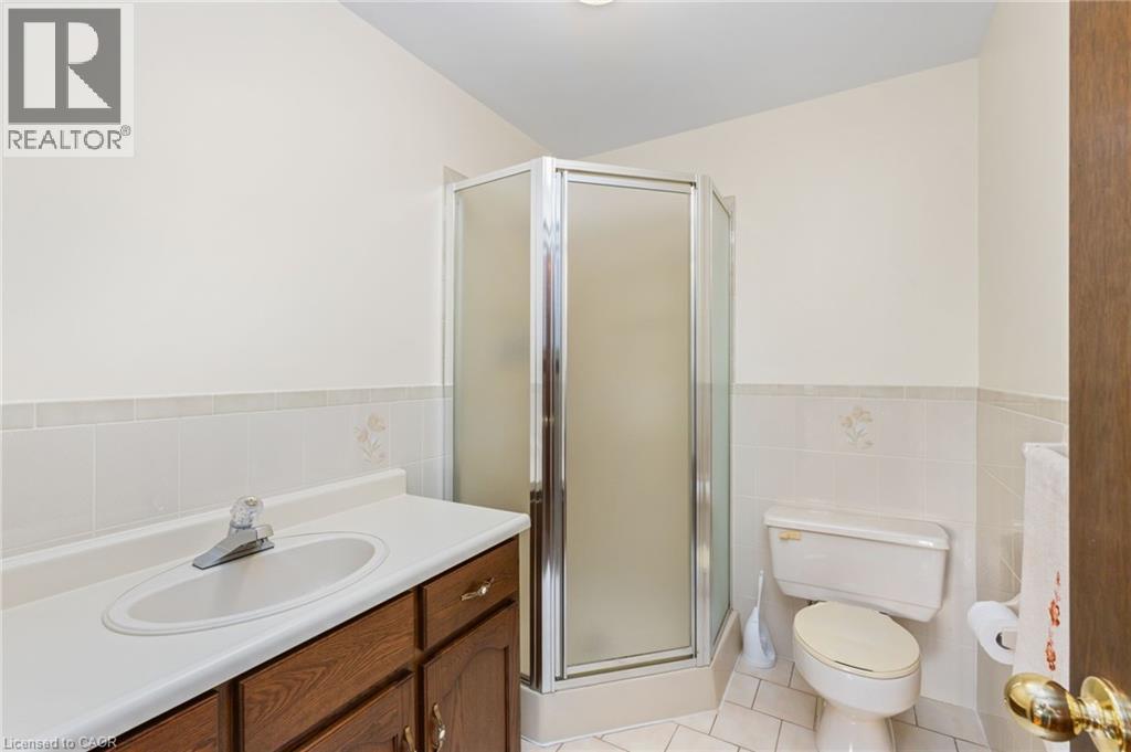 Full bath featuring light tile patterned flooring, a shower stall, vanity, tile walls, and wainscoting - 57 Derek Drive, Hamilton, ON - Indoor Photo Showing Bathroom