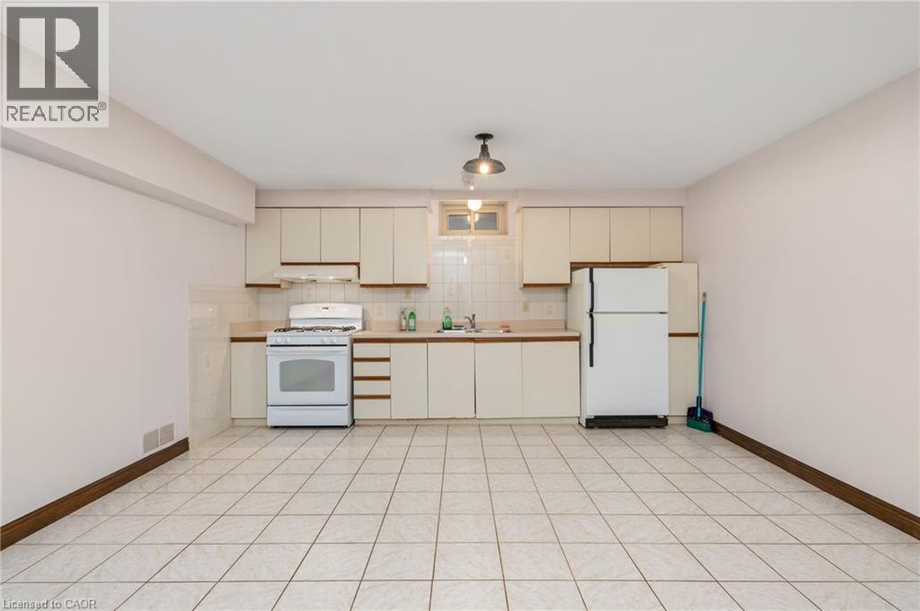 Kitchen featuring white appliances, cream cabinetry, light countertops, and tasteful backsplash - 57 Derek Drive, Hamilton, ON - Indoor Photo Showing Kitchen