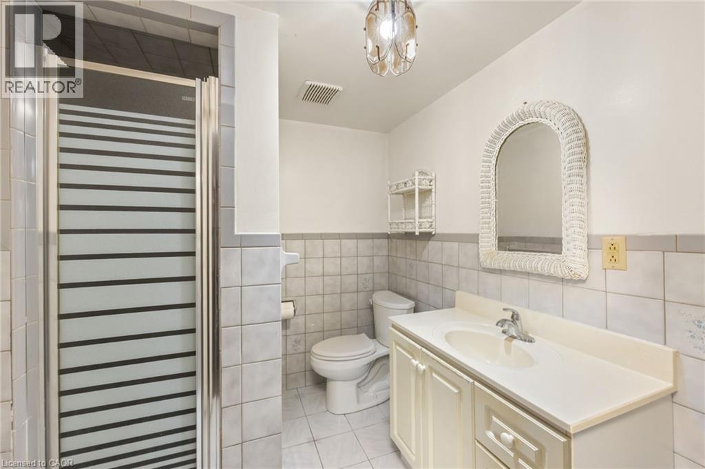 Full bathroom with vanity, tile walls, a stall shower, light tile patterned floors, and wainscoting - 57 Derek Drive, Hamilton, ON - Indoor Photo Showing Bathroom