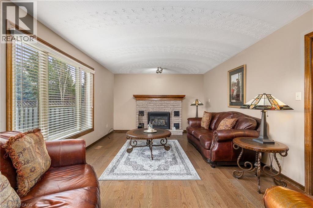 Living room with a brick fireplace, light wood-style flooring, and a textured ceiling - 57 Derek Drive, Hamilton, ON - Indoor Photo Showing Living Room With Fireplace