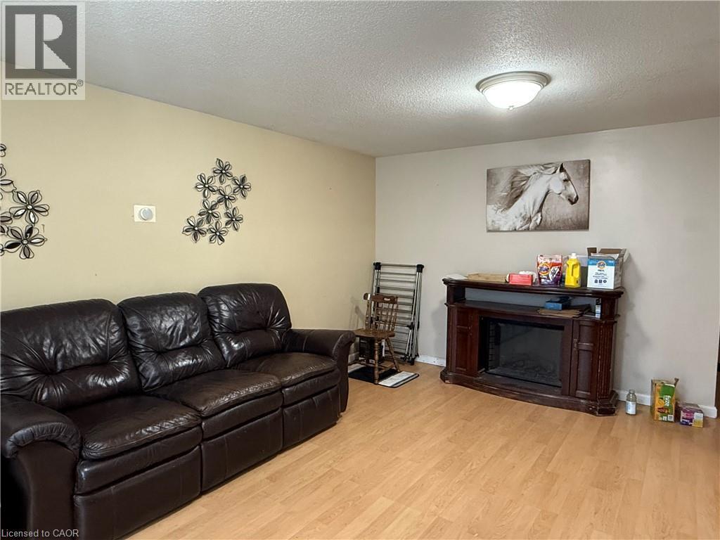 Living area with a textured ceiling, a glass covered fireplace, and light wood finished floors - 60 Helene Crescent, Waterloo, ON - Indoor Photo Showing Living Room With Fireplace