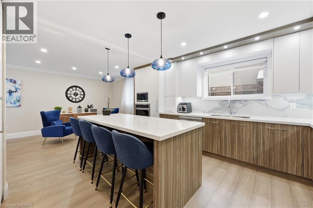 Dual tone kitchen featuring dual tone cabinetry, backsplash, modern cabinets, a kitchen island, and a kitchen breakfast bar - 273 Bryant Crescent, Burlington, ON - Indoor Photo Showing Kitchen With Upgraded Kitchen
