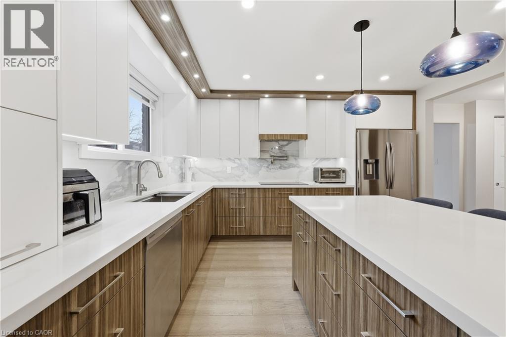 Dual tone kitchen with modern cabinets, two tone cabinets, stainless steel appliances, pendant lighting, and backsplash - 273 Bryant Crescent, Burlington, ON - Indoor Photo Showing Kitchen With Upgraded Kitchen