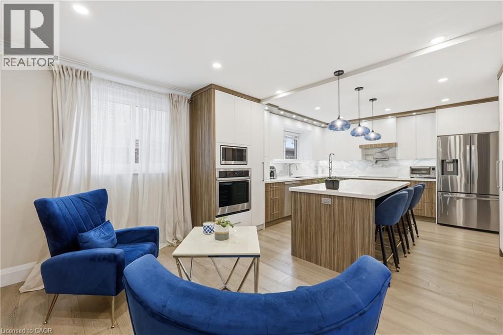 Kitchen with two tone cabinets, a kitchen island, light wood-style flooring, stainless steel appliances, and decorative backsplash - 273 Bryant Crescent, Burlington, ON - Indoor Photo Showing Kitchen With Upgraded Kitchen