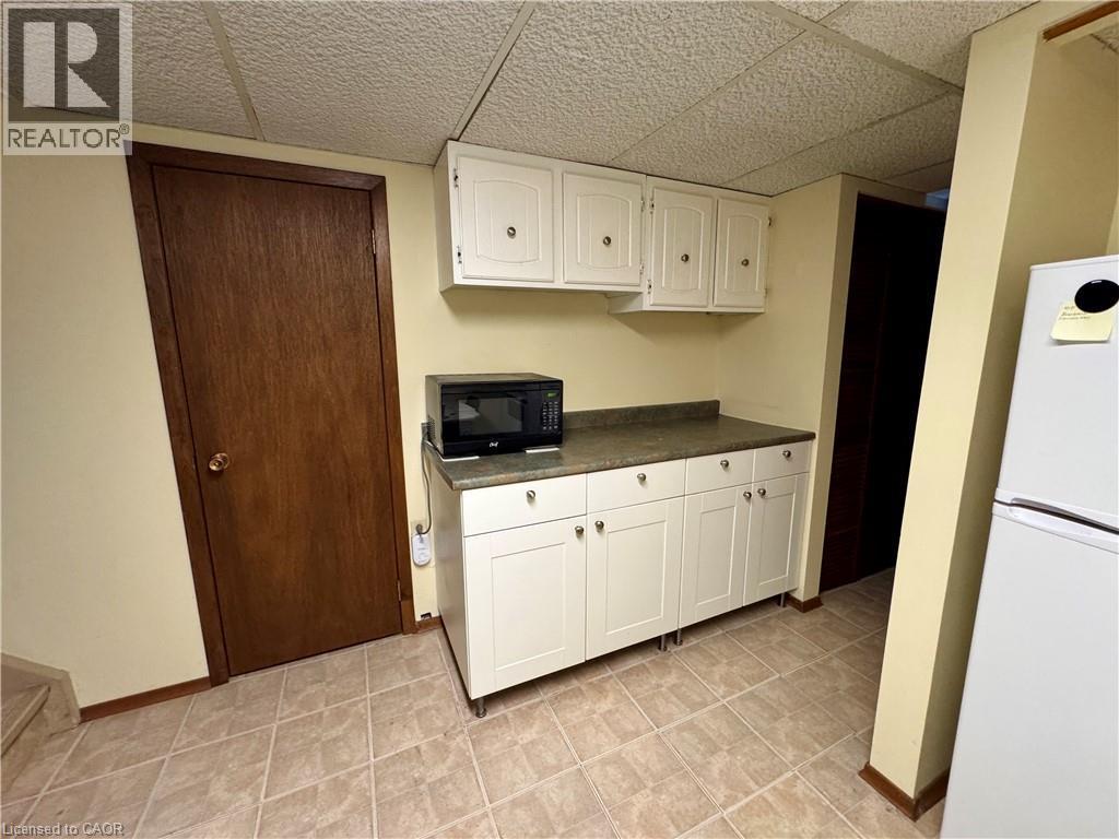 Kitchen with white cabinetry, freestanding refrigerator, dark countertops, black microwave, and a drop ceiling - 86 Devonglen Drive, Kitchener, ON - Indoor Photo Showing Kitchen