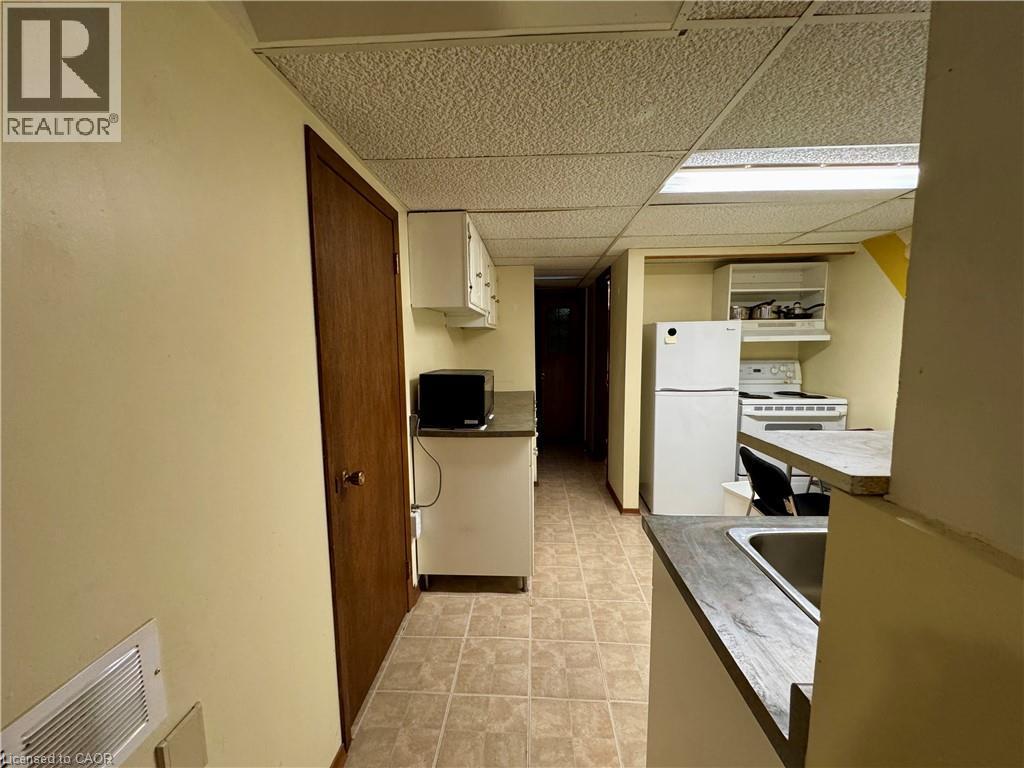 Kitchen featuring white appliances, white cabinetry, a drop ceiling, under cabinet range hood, and light countertops - 86 Devonglen Drive, Kitchener, ON - Indoor Photo Showing Kitchen