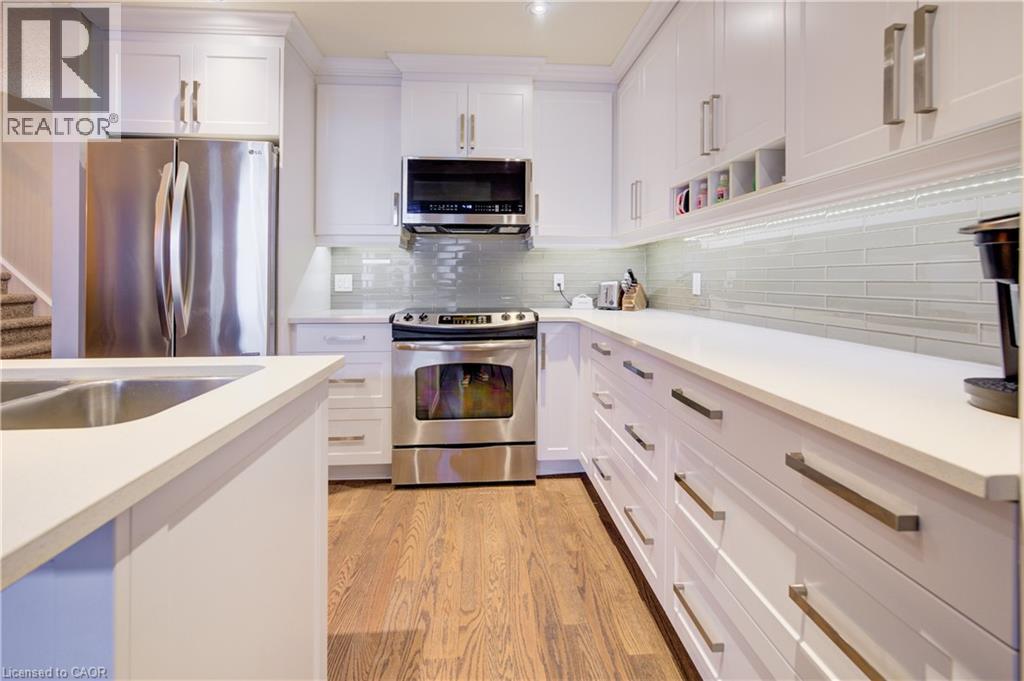 Kitchen with appliances with stainless steel finishes, white cabinetry, decorative backsplash, light wood-type flooring, and open shelves - 34 Harrison Street, Stratford, ON - Indoor Photo Showing Kitchen With Double Sink With Upgraded Kitchen