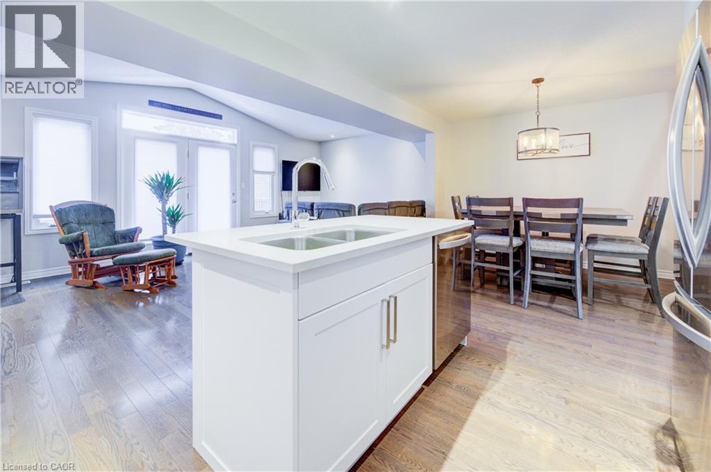 Kitchen with open floor plan, white cabinets, vaulted ceiling, decorative light fixtures, and a kitchen island with sink - 34 Harrison Street, Stratford, ON - Indoor