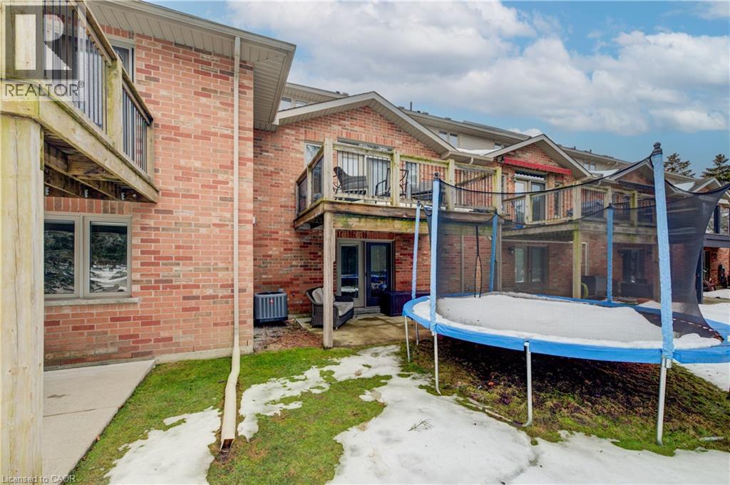 Back of house featuring a patio area, brick siding, a trampoline, and a balcony - 34 Harrison Street, Stratford, ON - Outdoor