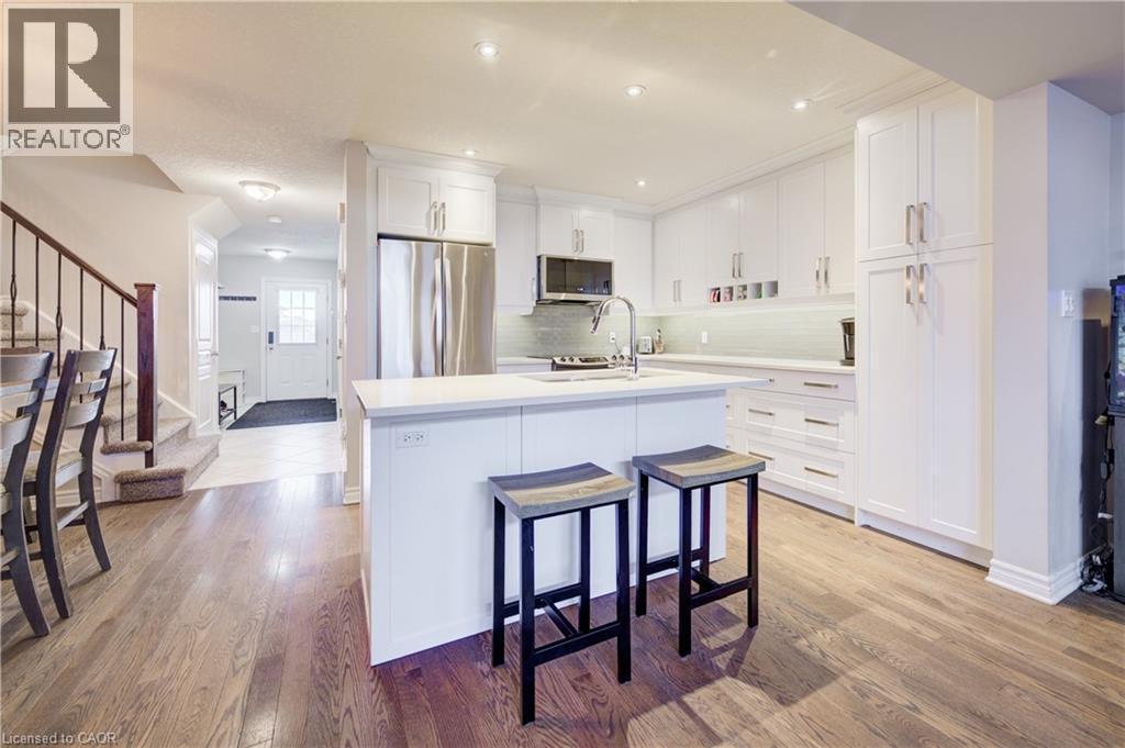 Kitchen featuring white cabinets, stainless steel appliances, a breakfast bar area, an island with sink, and light wood-style floors - 34 Harrison Street, Stratford, ON - Indoor Photo Showing Kitchen With Upgraded Kitchen