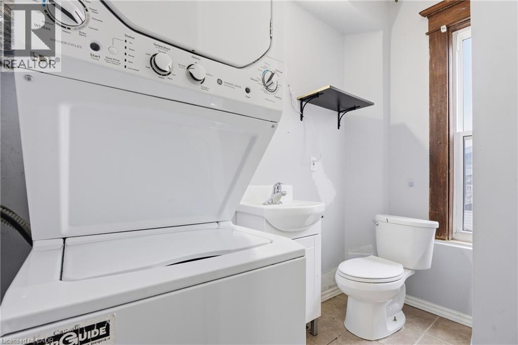 Full bath with vanity, stacked washer / dryer, light tile patterned floors, and shower / bathtub combination - 30 Regina Street N, Waterloo, ON - Indoor Photo Showing Laundry Room