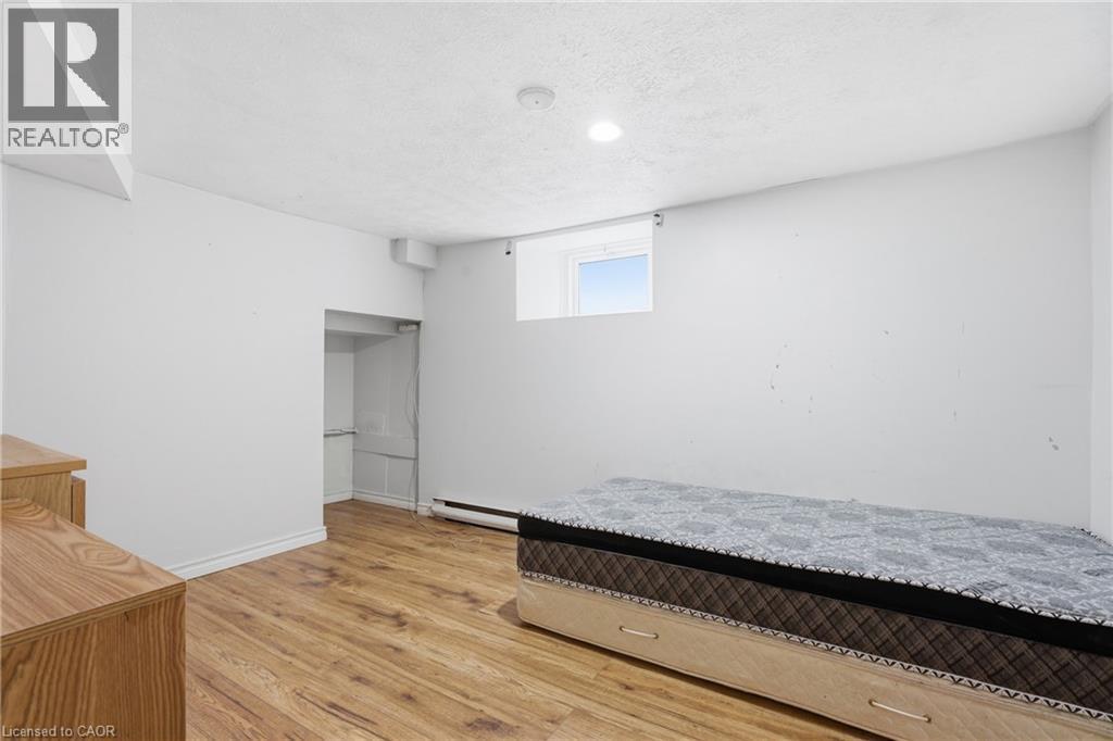 Unfurnished bedroom featuring light wood-type flooring, a baseboard radiator, and a textured ceiling - 30 Regina Street N, Waterloo, ON - Indoor Photo Showing Bedroom