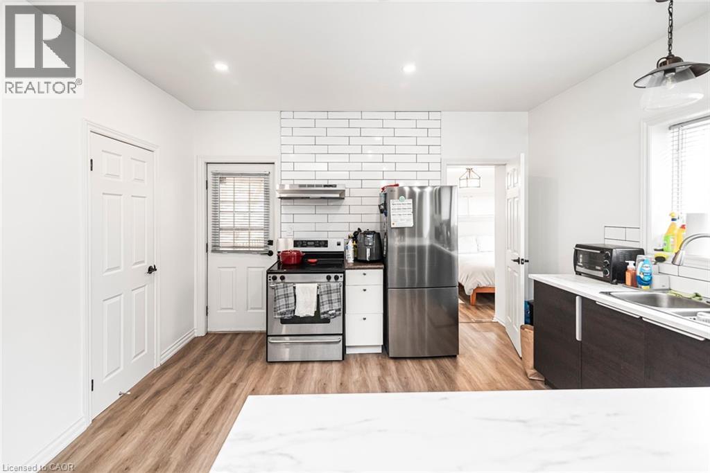 Kitchen featuring stainless steel appliances, light wood finished floors, light countertops, and dark wood finish cabinets - 57 New Street, Hamilton, ON - Indoor Photo Showing Kitchen