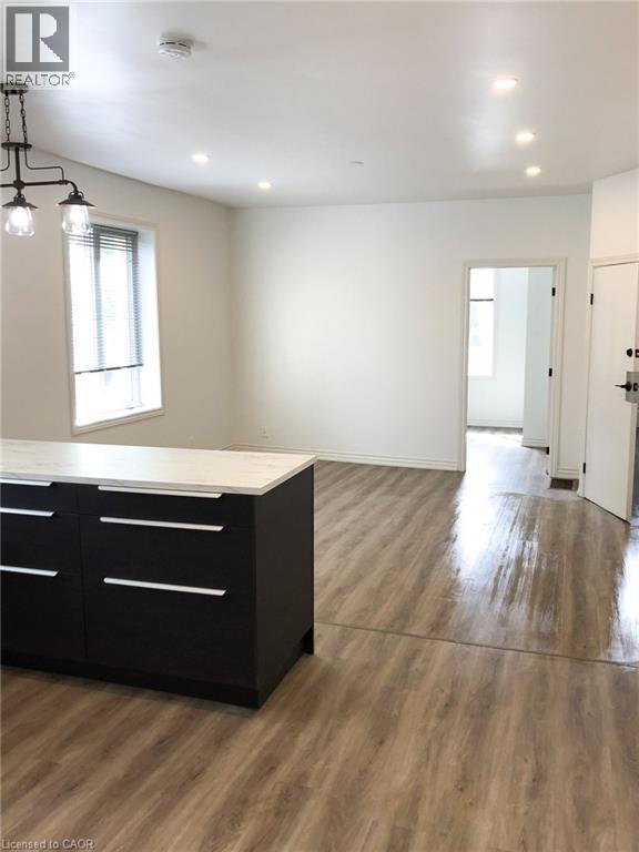 Kitchen featuring dark cabinetry, light countertops, dark wood finished floors, pendant lighting, and open floor plan - 57 New Street, Hamilton, ON - Indoor Photo Showing Other Room