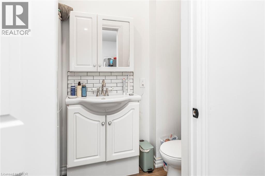 Half bath with vanity, wood finished floors, and decorative backsplash - 57 New Street, Hamilton, ON - Indoor Photo Showing Bathroom