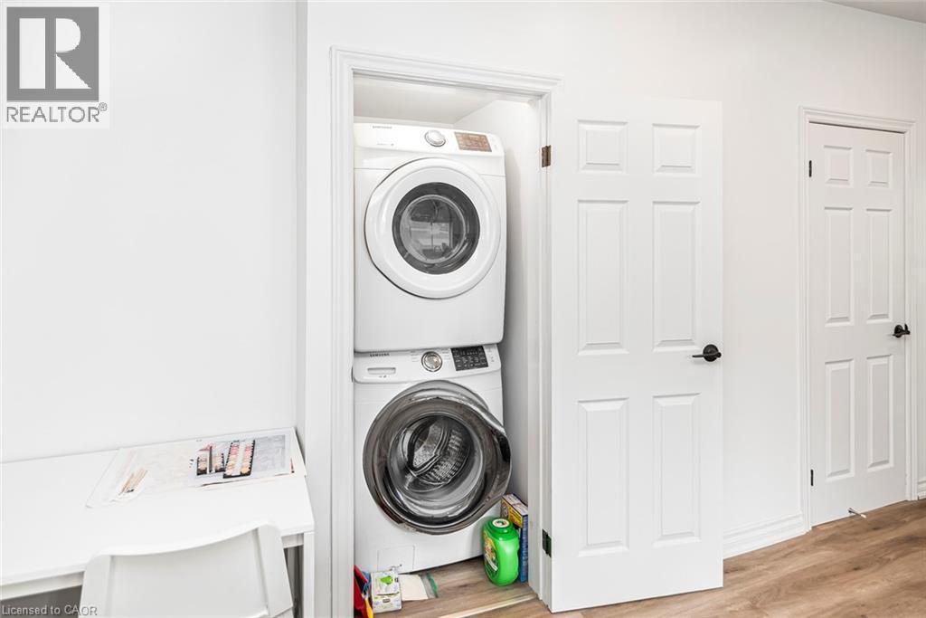 Laundry room with stacked washer / drying machine and light wood finished floors - 57 New Street, Hamilton, ON - Indoor Photo Showing Laundry Room
